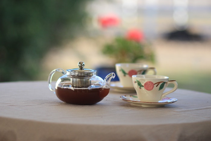 clear_glass_teapot_near_teacups_on_table 