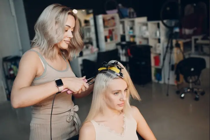 hairdresser_female_making_hair_extensions_to_young_woman_with_blonde_hair